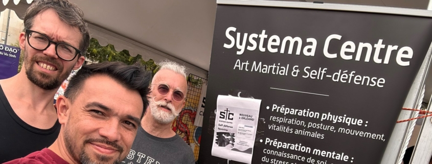 Trois membres du Systema Centre au stand du club, place du Martroi, devant le kakémono présentant l’art martial et la self-défense